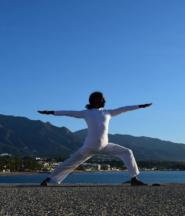 Silhouette of a person in a yoga pose against a sunrise.