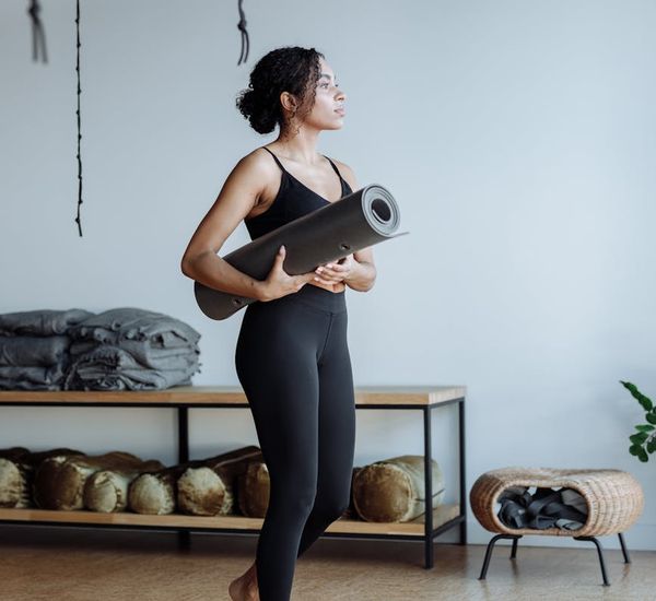 Woman holding a strong warrior yoga pose in a studio.